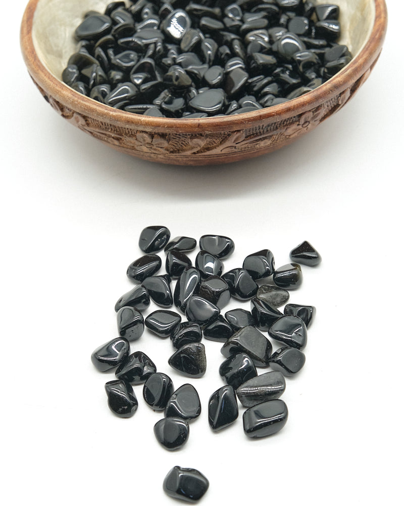 Black Obsidian stones in a wooden bowl on a white background