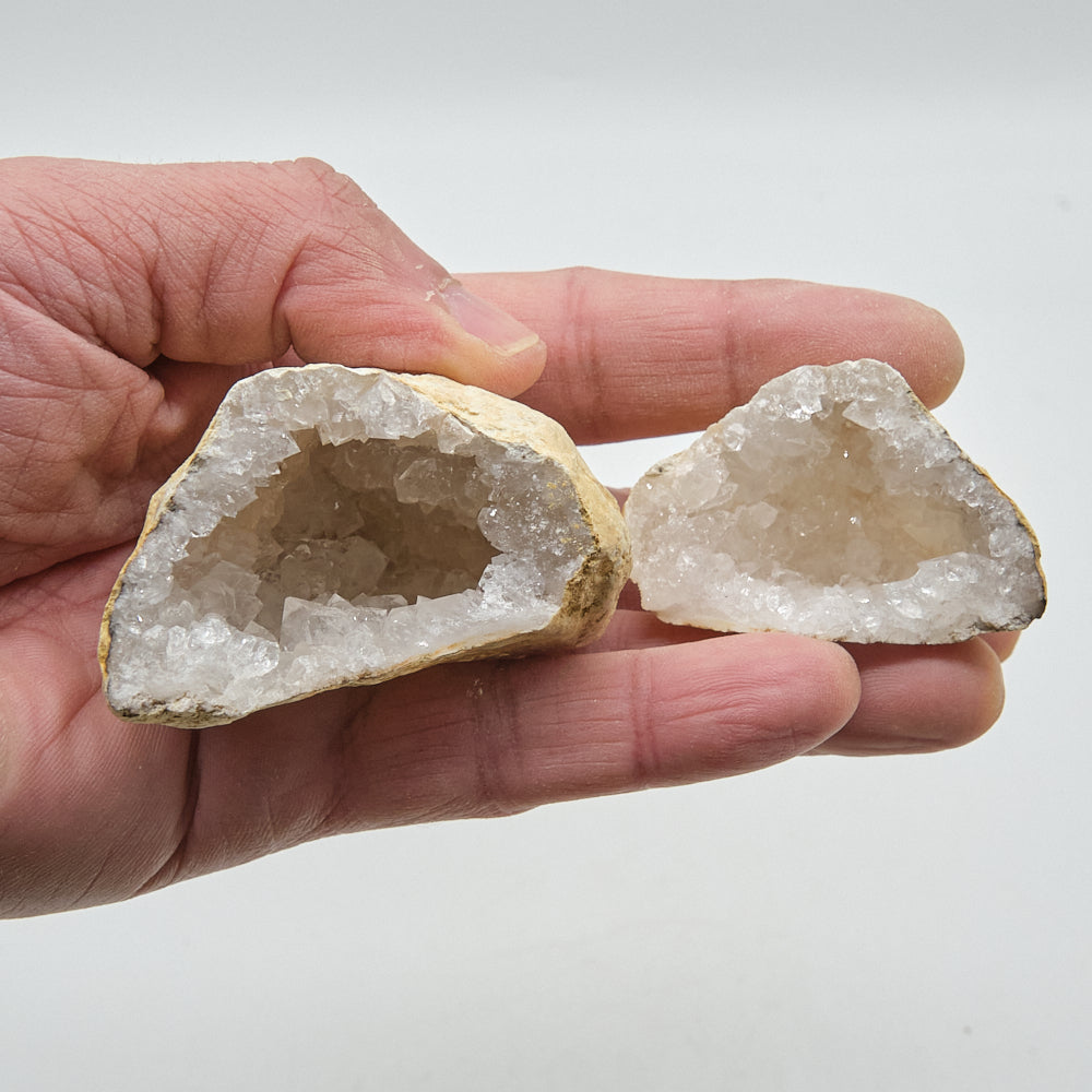 Two crystal geodes held in a hand against a white background